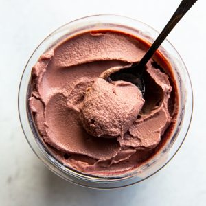 chocolate cherry ice cream in a clear pint with a spoon.