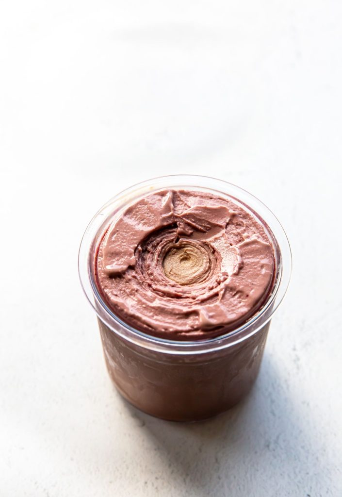 chocolate cherry ice cream in a clear pint container.