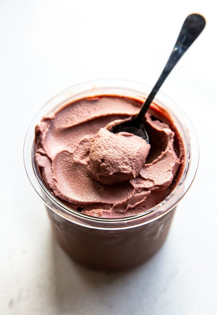 chocolate cherry ice cream in a clear pint with a spoon.