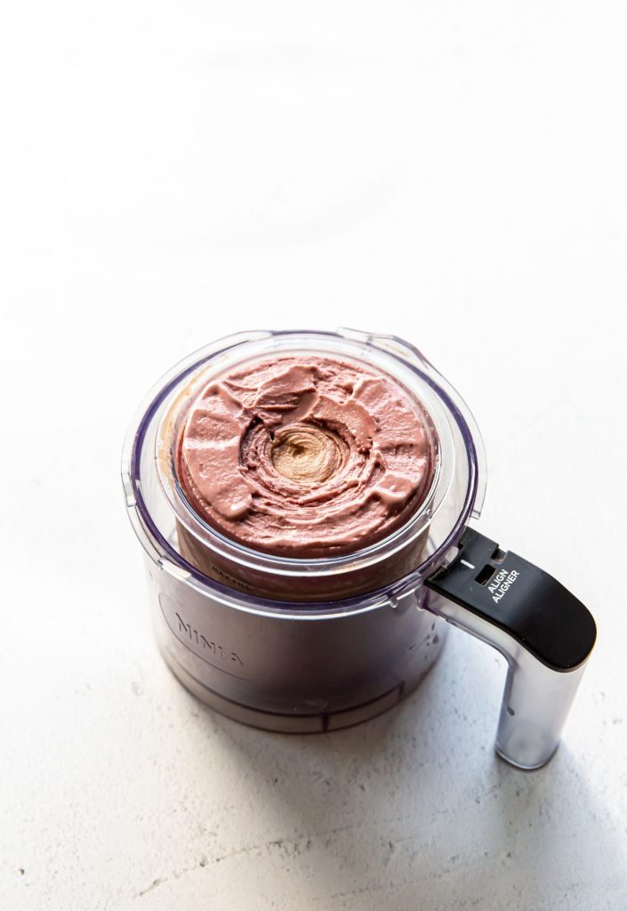 chocolate cherry ice cream in a clear pint container in the Ninja CREAMi pint holder.