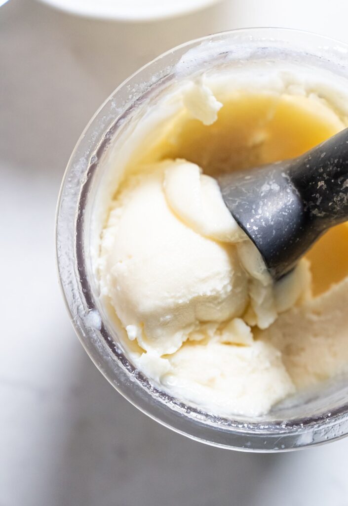 dole whip in a ninja creami pint with a ice cream scoop.