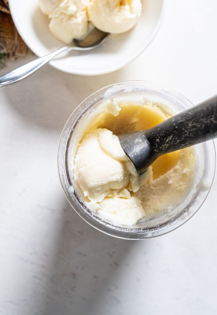 dole whip in a ninja creami pint with a ice cream scoop.