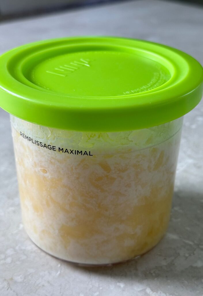 pineapple, milk and vanilla in a clear pint with a green lid.