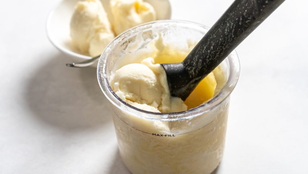 dole whip in a ninja creami pint with a ice cream scoop.