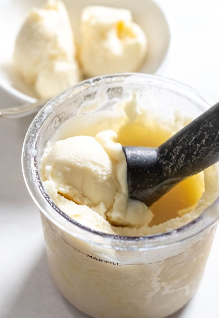 dole whip in a ninja creami pint with a ice cream scoop.