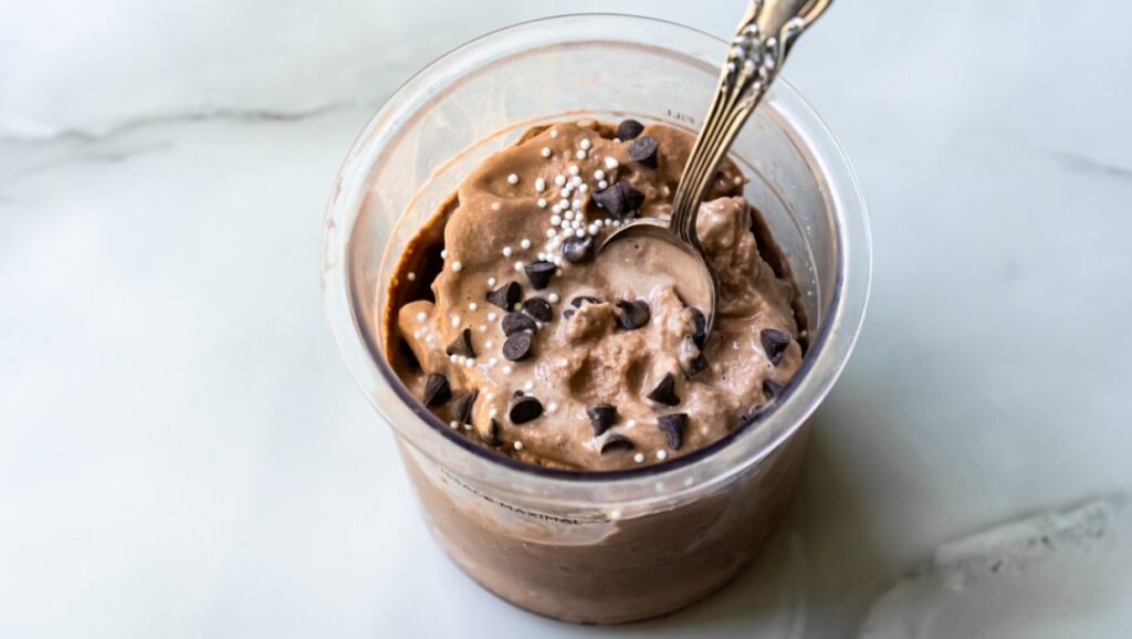 chocolate ice cream with chocolate chips and sprinkles and a spoon.