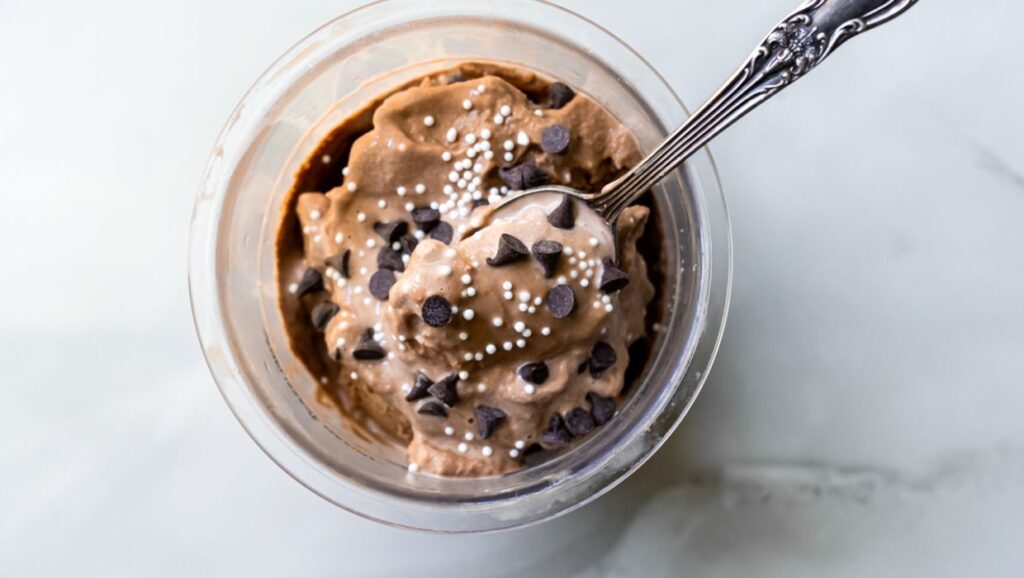 chocolate ice cream with chocolate chips and sprinkles and a spoon.