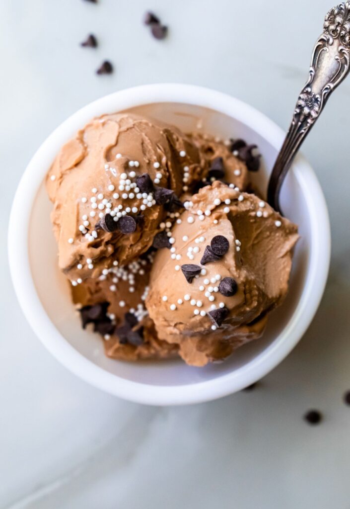 chocolate ice cream with chocolate chips and sprinkles and a spoon.