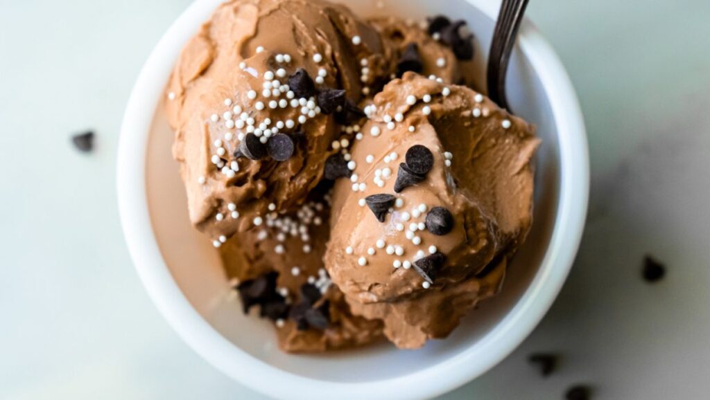 chocolate ice cream with chocolate chips and sprinkles and a spoon.