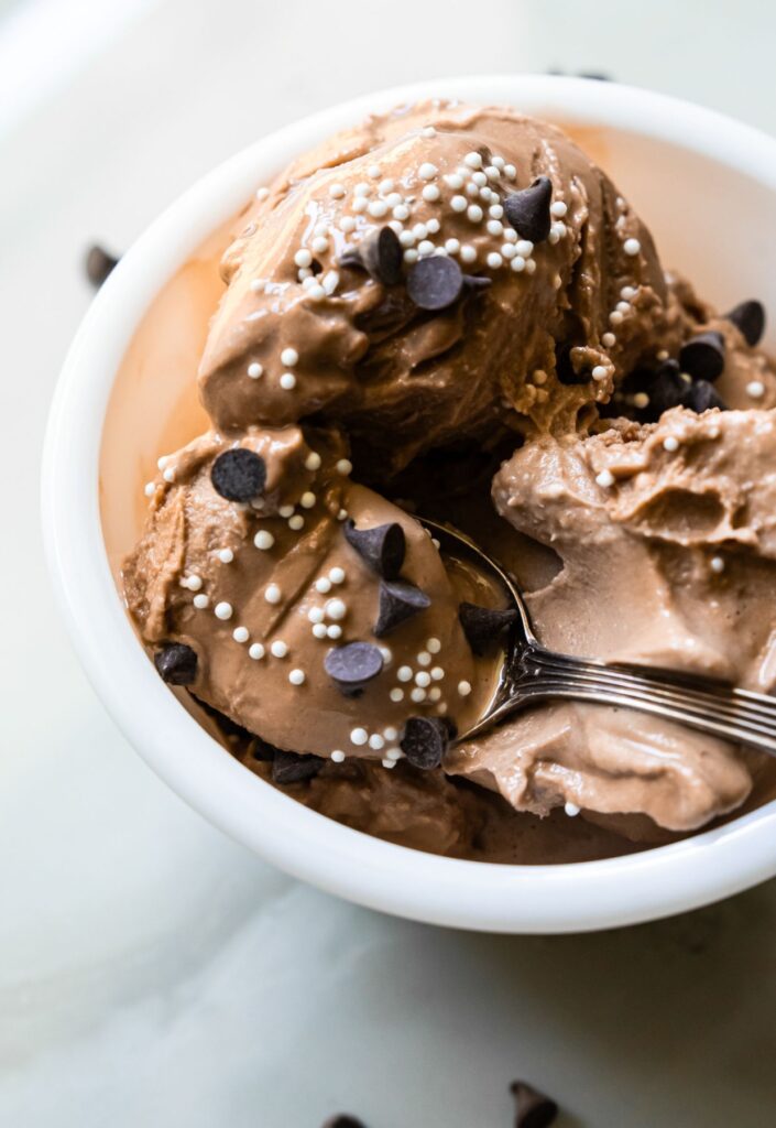 chocolate ice cream with chocolate chips and sprinkles and a spoon.