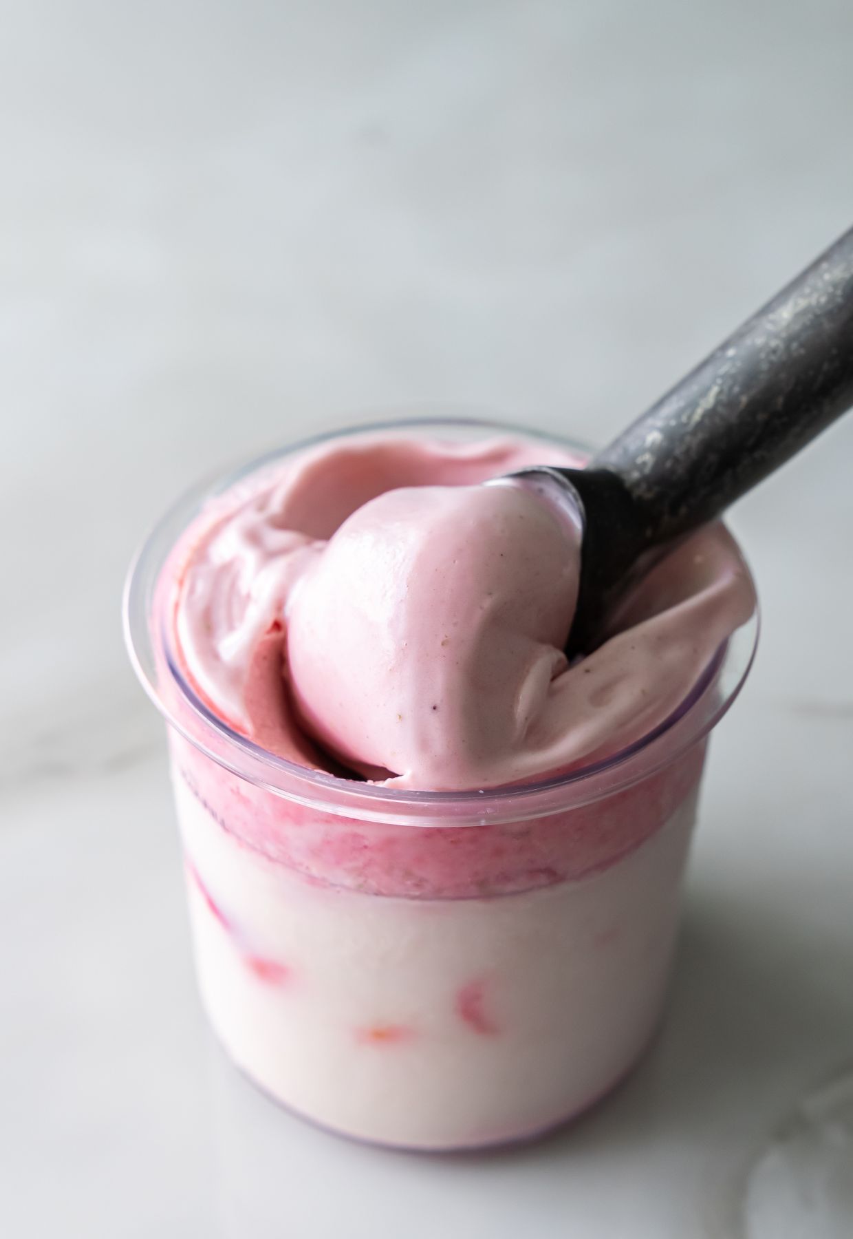 Ninja Creami strawberry ice cream in a pint container with scoop.