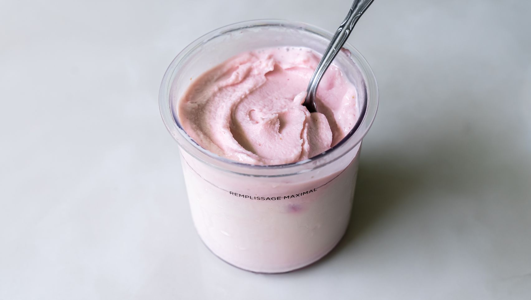 Ninja Creami strawberry ice cream in a pint container with spoon.