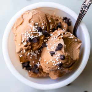 chocolate ice cream with sprinkles and chocolate chips with a spoon.
