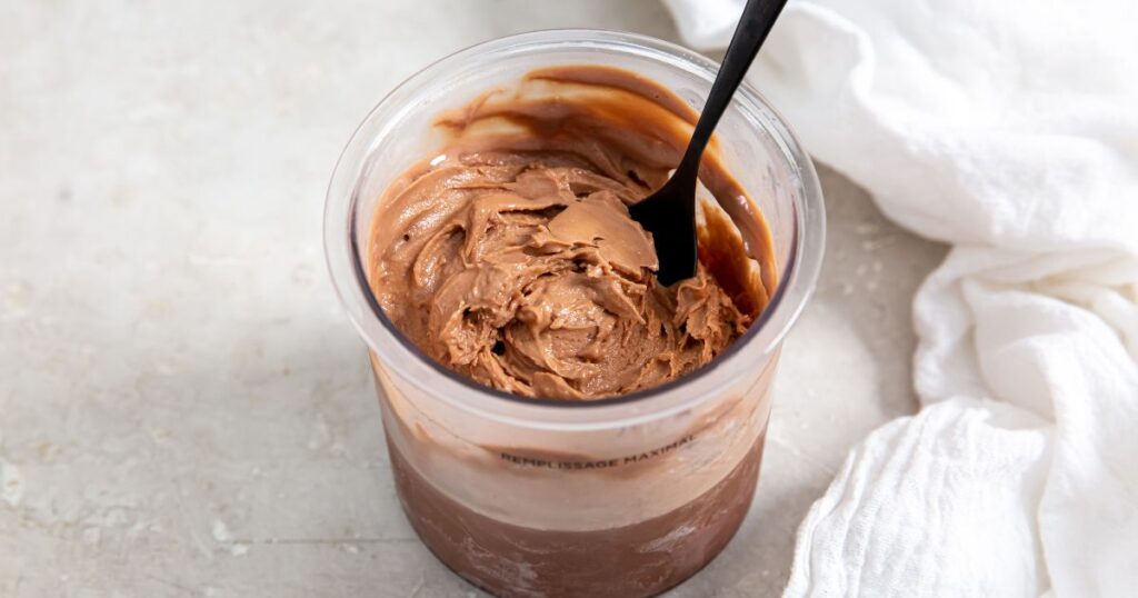 Chocolate Protein Ice Cream without banana in a small transparent cup with a fork.