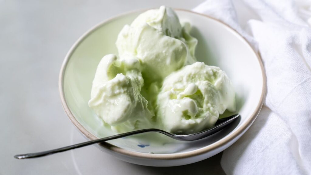 Pistachio ice cream in a bowl with a spoon.
