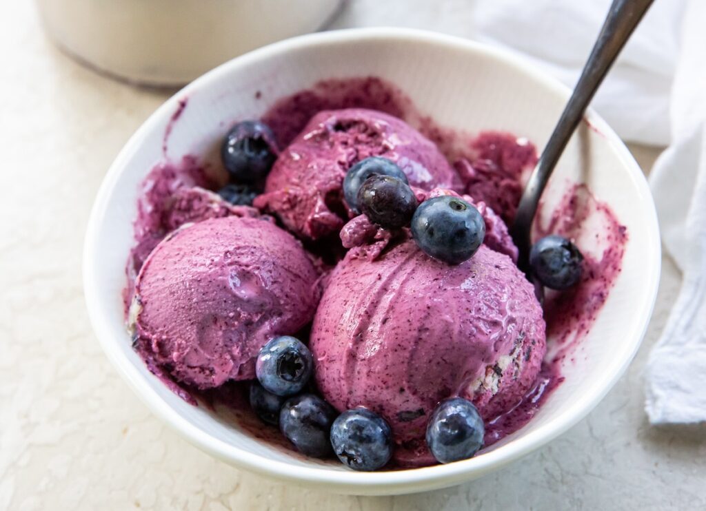 Ninja CREAMi Blueberry Ice Cream in a bowl topped with fresh blueberries.