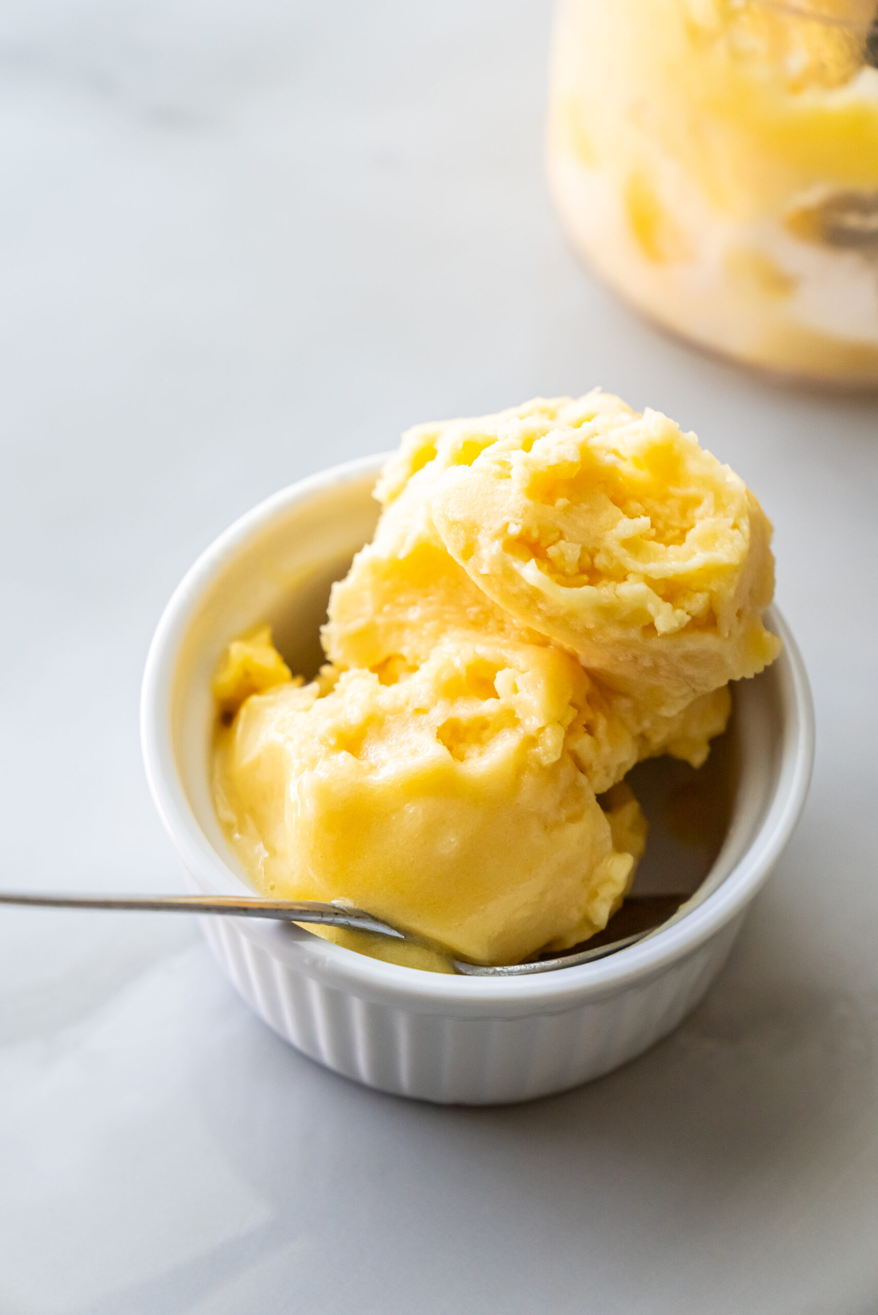 peach sorbet in a white bowl with a spoon.