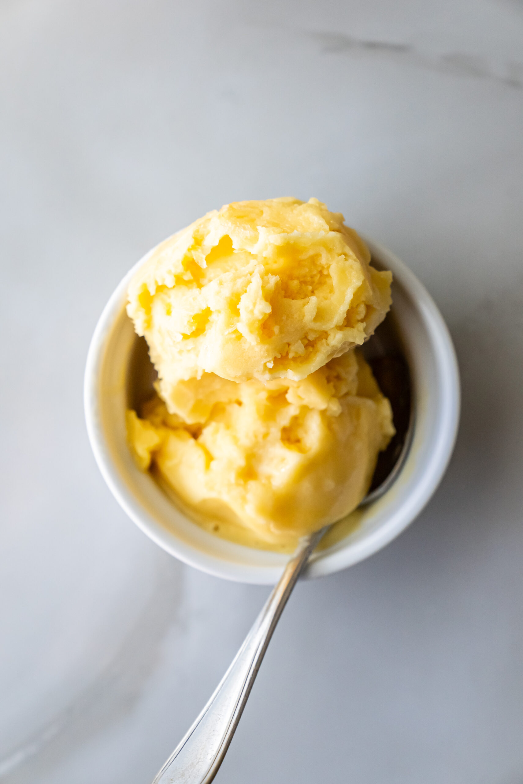 peach sorbet in a white bowl with a spoon.