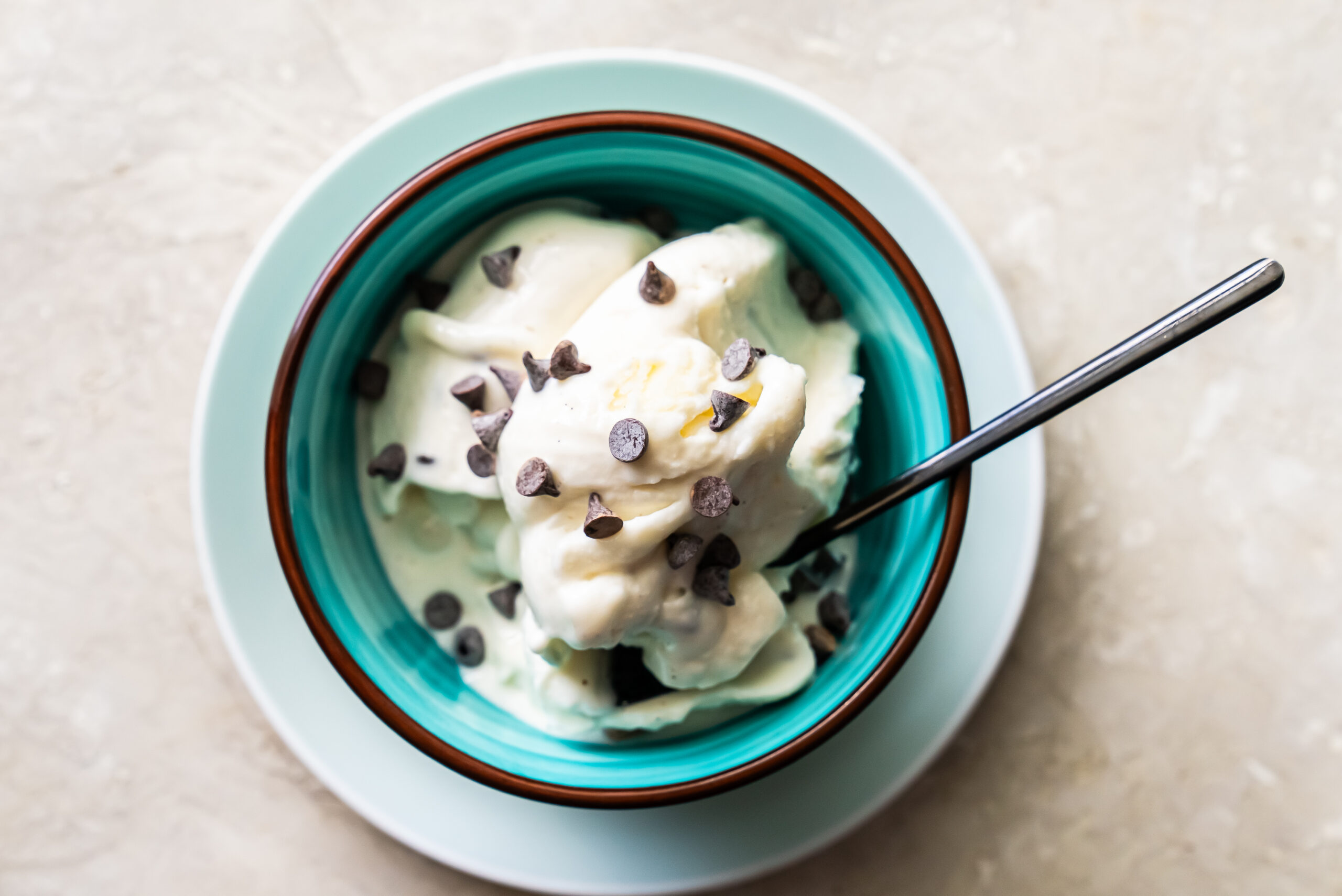 ice cream in a blue bowl topped with chocolate chips.