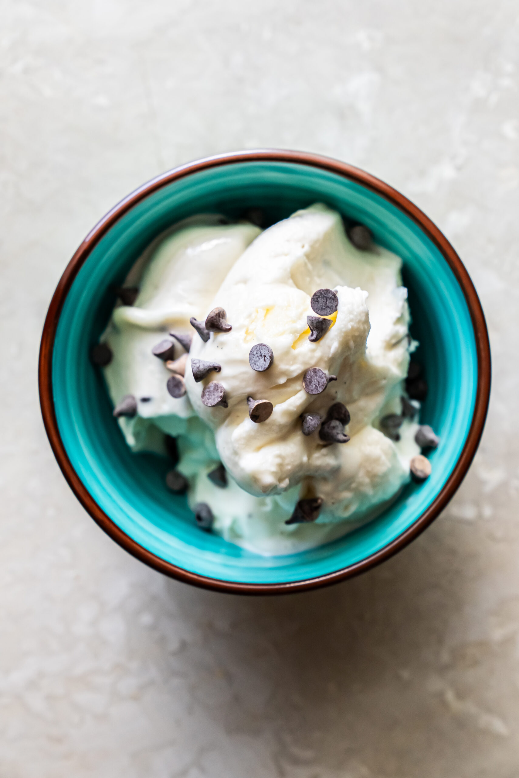 ice cream in a blue bowl topped with chocolate chips.